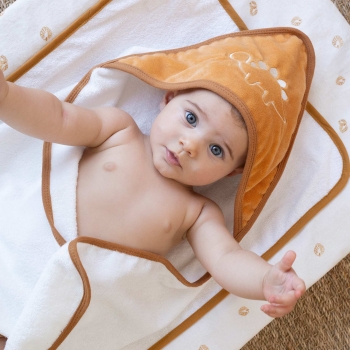 O bebé bem quentinho na sua capa de banho cor de camelo O bebé bem quentinho na sua capa de banho cor de camelo