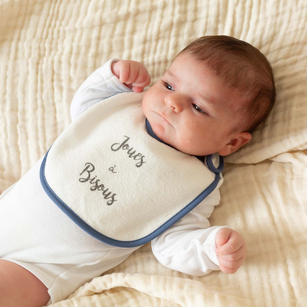 Baby mit seinem marineblauen Lätzchen um den Hals Baby mit seinem marineblauen Lätzchen um den Hals
