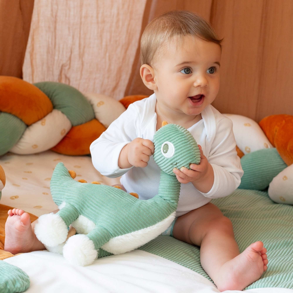 Bebé a brincar com o seu peluche musical em forma de diplodoco