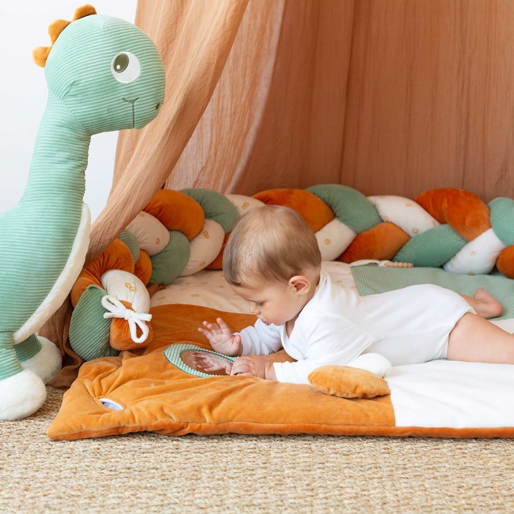 Bambino che si guarda allo specchio con il suo grande peluche diplodoco accanto