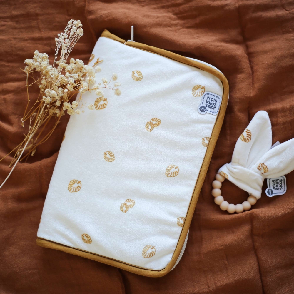 Health record book cover placed on the camel-colored swaddle