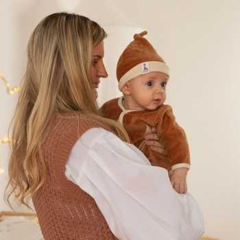 Bebé com o seu gorro Sophie la girafe camel ao colo da mãe Bebé com o seu gorro Sophie la girafe camel ao colo da mãe