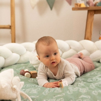 bébé dans son espace jeu avec sa tresse de lit