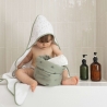 Bebé à saída do banho com a sua toalha de banho com capuz e o seu cesto de produtos de higiene Bebé à saída do banho com a sua toalha de banho com capuz e o seu cesto de produtos de higiene