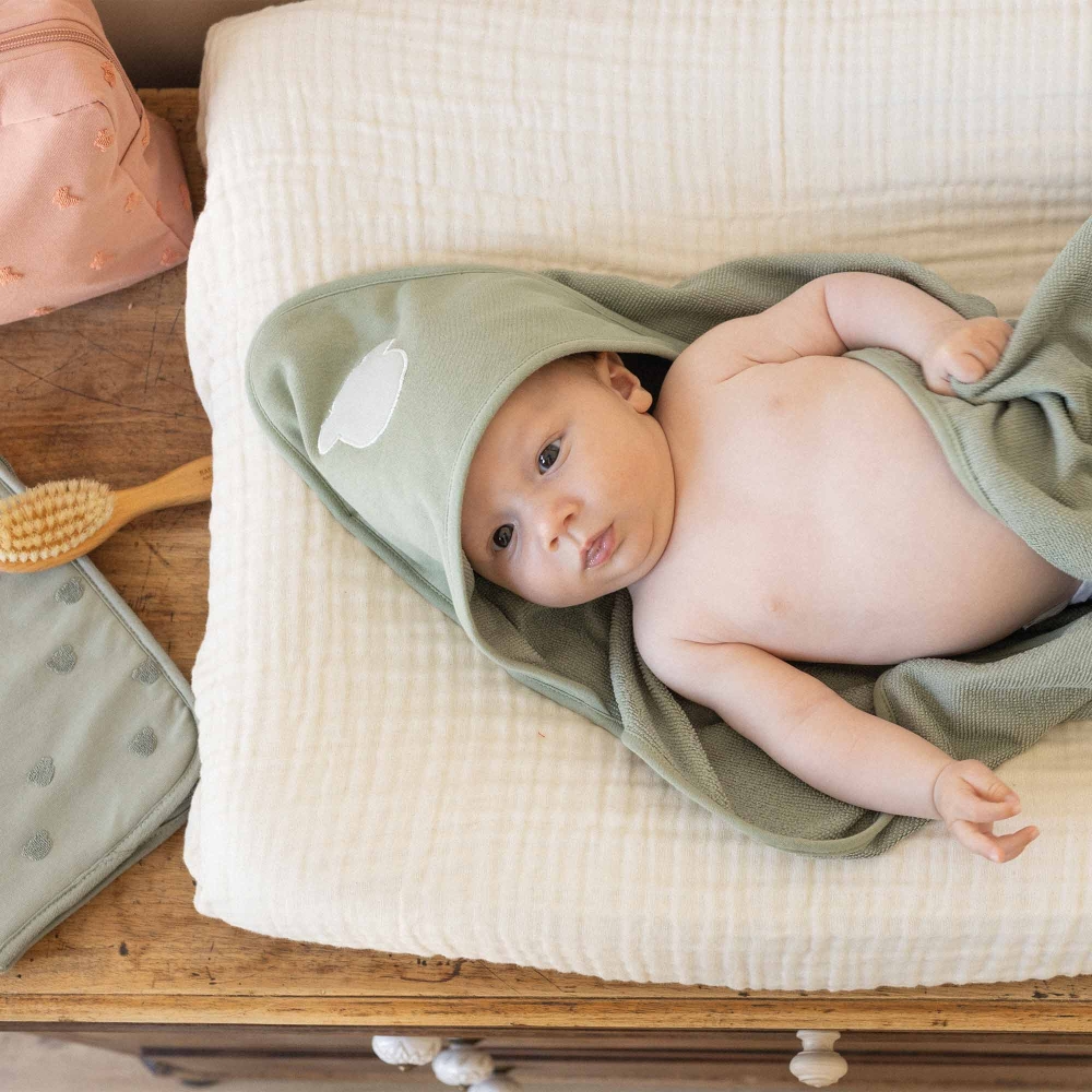 bébé sur matelas à langer avec sa cape de bain bébé