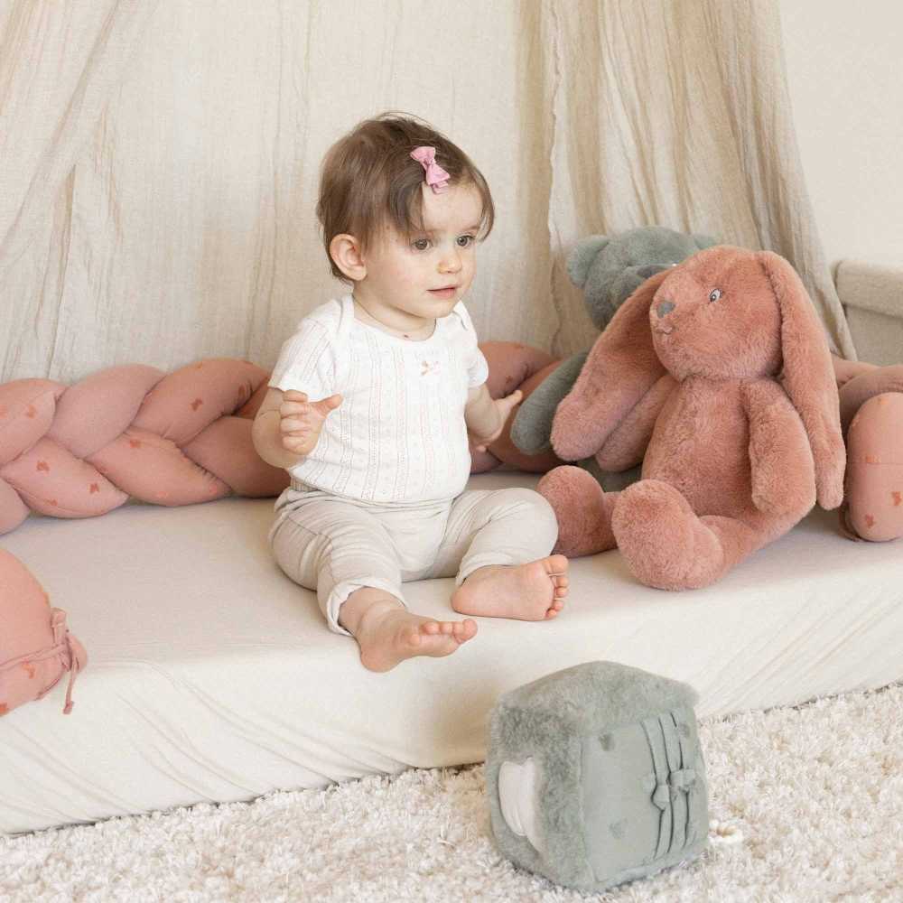 Bebé sentado com a sua trança decorativa para criar o seu espaço de brincadeira Bebé sentado com a sua trança decorativa para criar o seu espaço de brincadeira