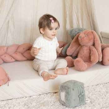 Bebé sentado com a sua trança decorativa para criar o seu espaço de brincadeira Bebé sentado com a sua trança decorativa para criar o seu espaço de brincadeira