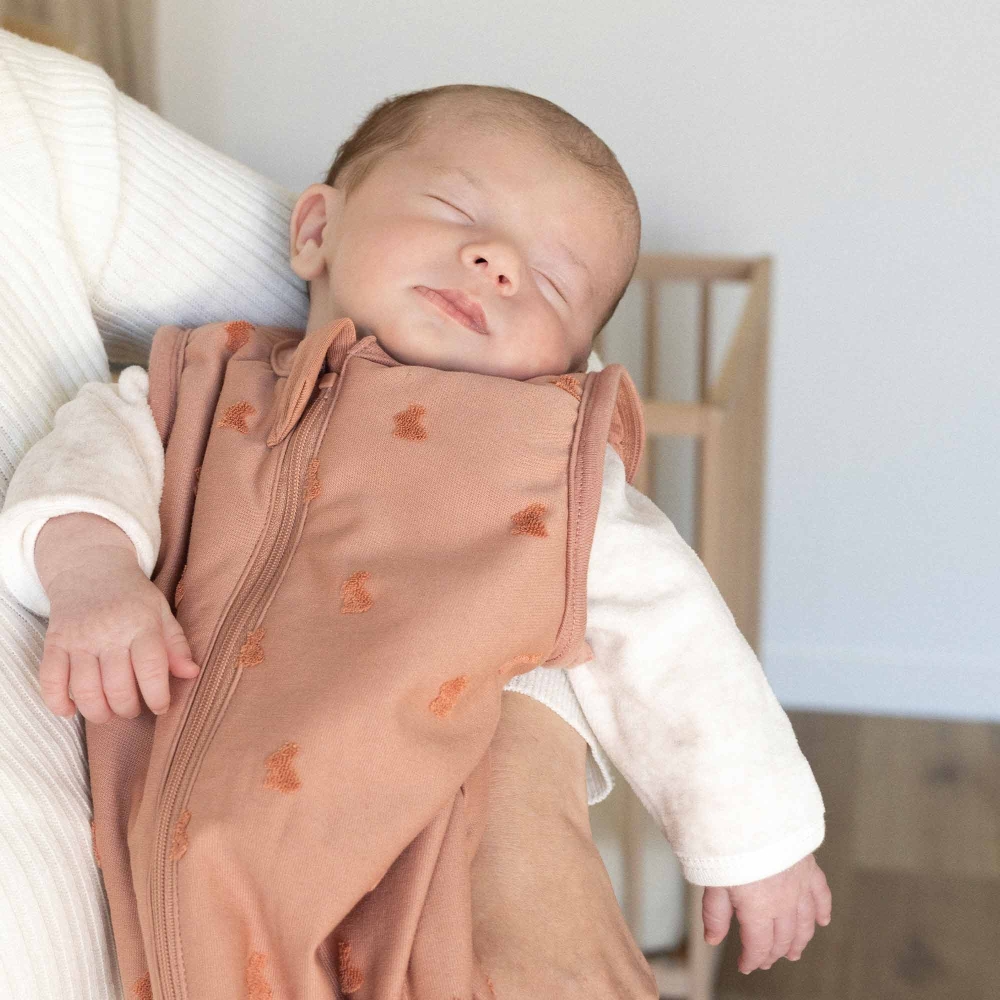 Baby in den Armen seiner Mama mit seinem Schlafsack Baby in den Armen seiner Mama mit seinem Schlafsack