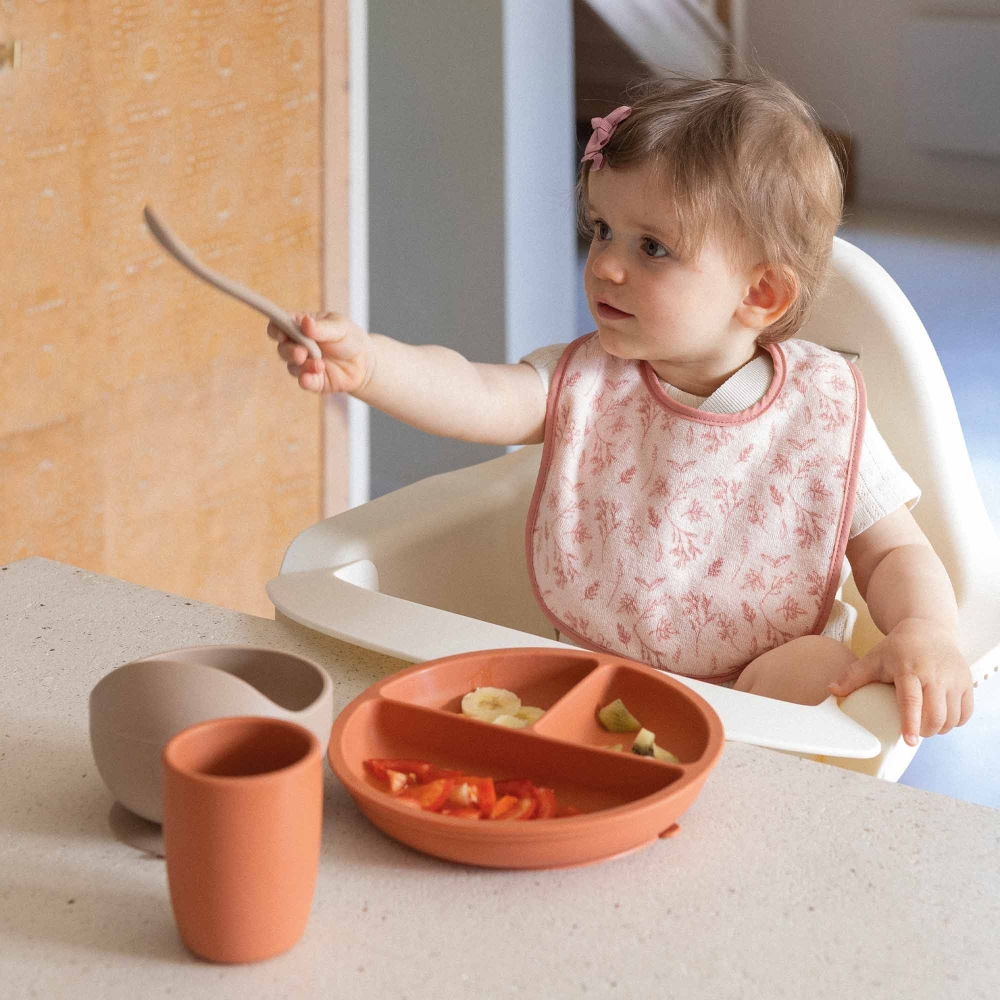 bambino con il suo bavaglino rosa che mangia