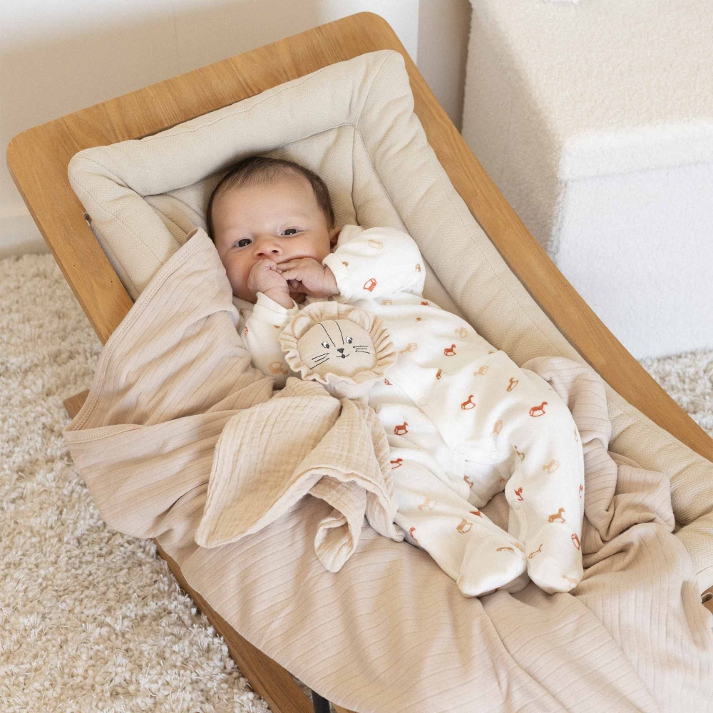 Baby in seiner Babywippe im Pyjama mit seiner Decke