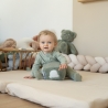 bebé a brincar com um cubo de atividades, vestido com um pijama de algodão verde-sálvia bebé a brincar com um cubo de atividades, vestido com um pijama de algodão verde-sálvia