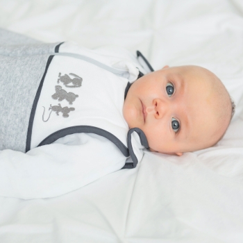 bebé niño de ojos azules acostado en su cuna con su saco de dormir nacimiento mixto