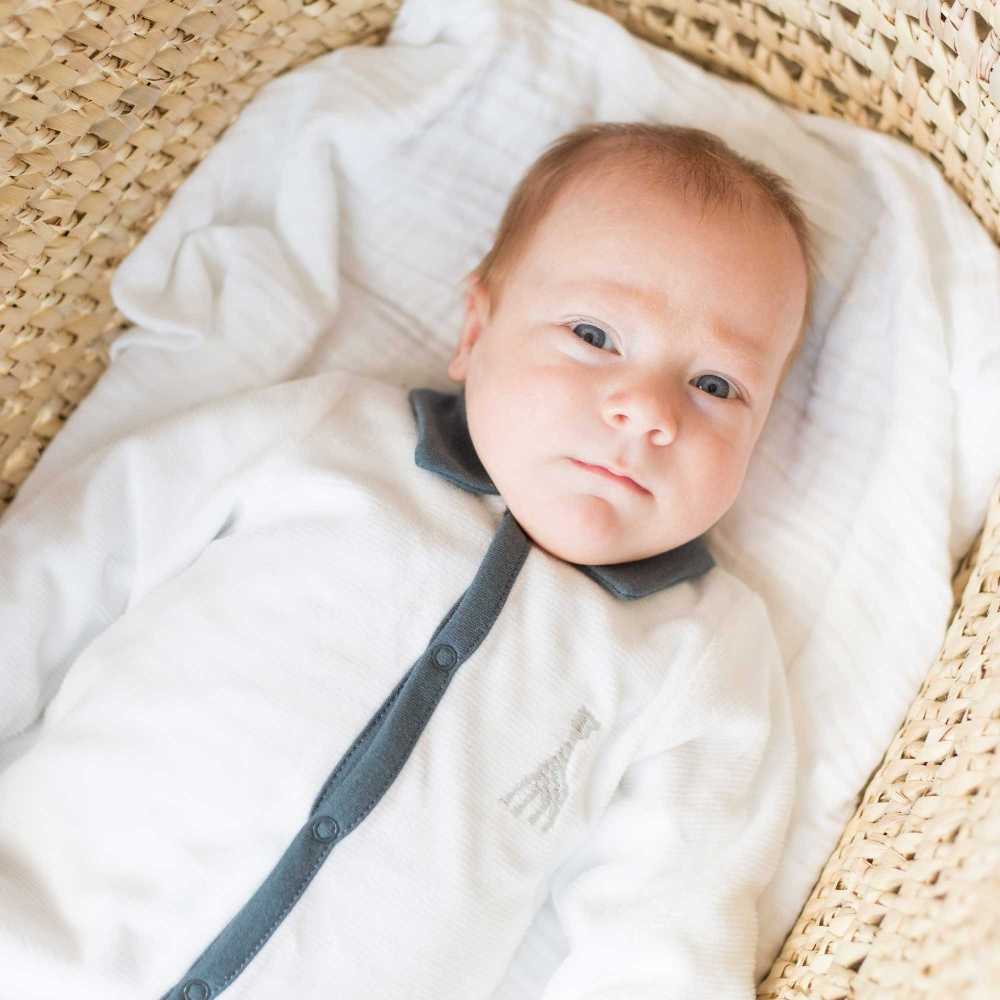 Bebé com pijama branco e azul de gola polo
