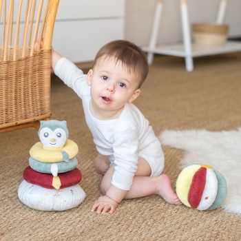 Bébé qui joue avec sa balle d'éveil et sa tour empilable.
