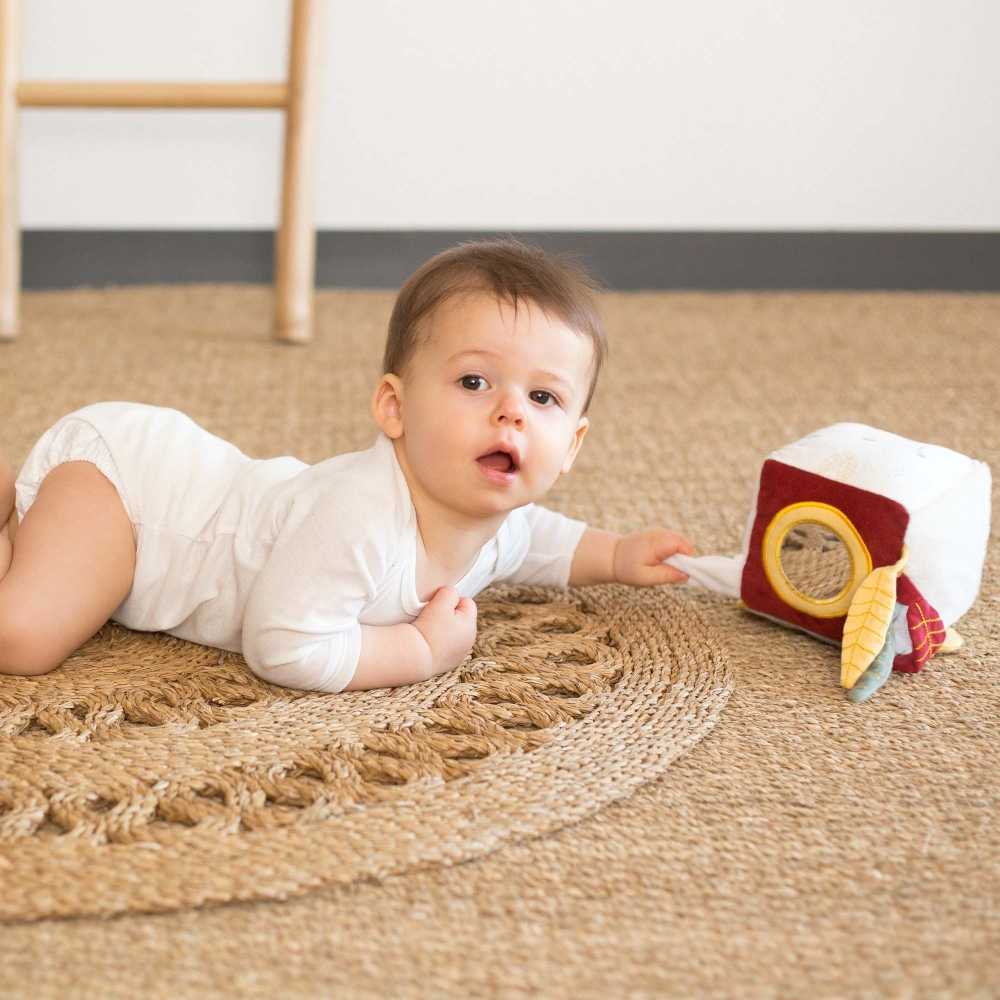 Bebé num tapete a brincar com o seu cubo sensorial. Bebé num tapete a brincar com o seu cubo sensorial.