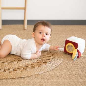 Bebé num tapete a brincar com o seu cubo sensorial. Bebé num tapete a brincar com o seu cubo sensorial.