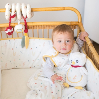 Baby zittend in zijn bed in slaapzak vergezeld van zijn muzikale knuffel Baby zittend in zijn bed in slaapzak vergezeld van zijn muzikale knuffel