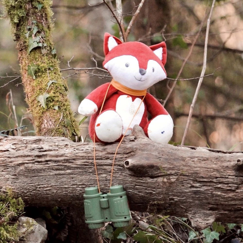 Muzikale knuffel vos zittend op een boomstam in het bos Muzikale knuffel vos zittend op een boomstam in het bos
