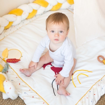Little girl sitting on her play mat surrounded by the decorative braid Little girl sitting on her play mat surrounded by the decorative braid