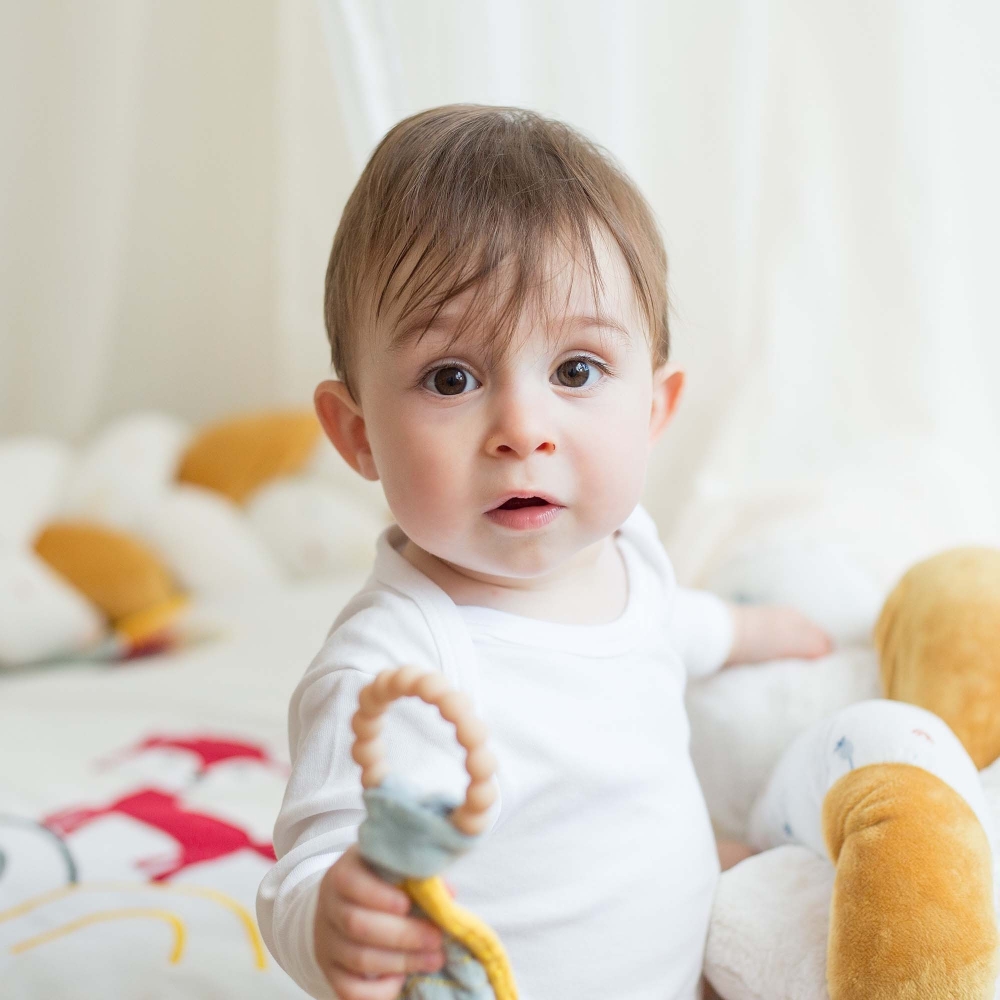 Baby with teething rattle on activity mat Baby with teething rattle on activity mat