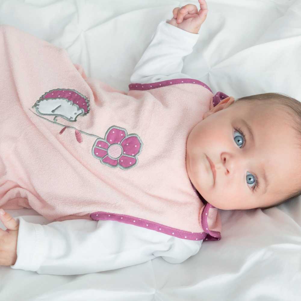 Bebé de olhos azuis com o seu saco-cama de verão rosa-salmão Bebé de olhos azuis com o seu saco-cama de verão rosa-salmão