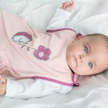 Bebé de olhos azuis com o seu saco-cama de verão rosa-salmão Bebé de olhos azuis com o seu saco-cama de verão rosa-salmão