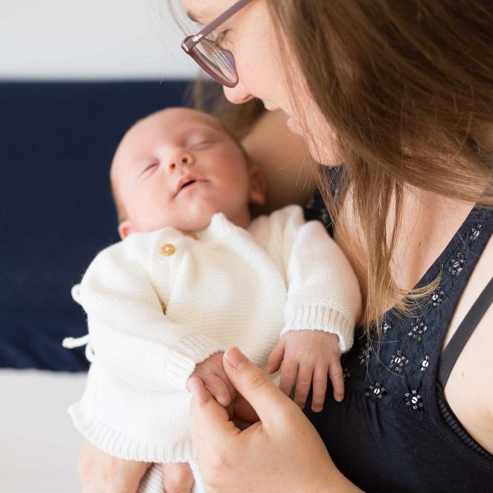 baby in wit gebreid vestje in boordsteek met zijn mama