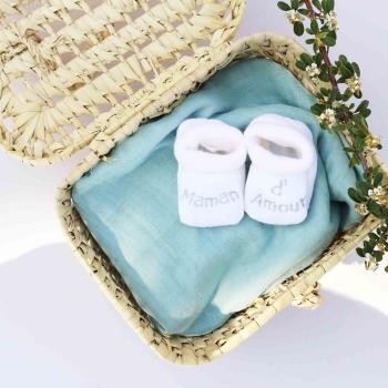 zapatillas de bebé en cesta de mimbre y fondo verde salvia