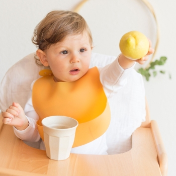 Bebè a tavola con il suo bavaglino in silicone