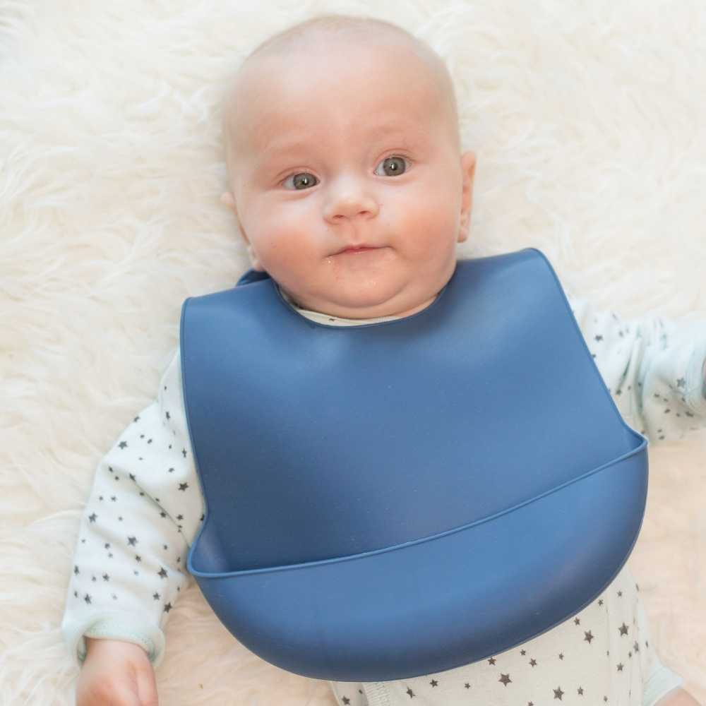 Bebé com o seu babete de silicone azul-marinho, tão bonito