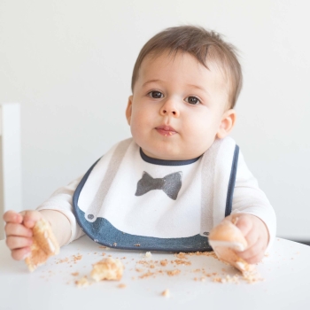 Bebé comiendo su pastel protegido con su babero caballero Bebé comiendo su pastel protegido con su babero caballero