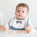 Bebé a comer o seu bolo, protegido pelo seu babete Gentleman Bebé a comer o seu bolo, protegido pelo seu babete Gentleman