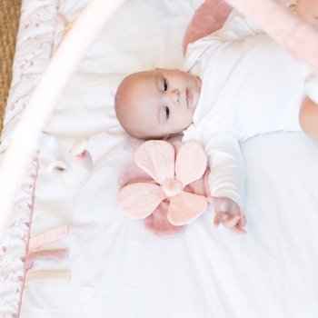 Baby on her pretty pink and white play mat with activity arches Baby on her pretty pink and white play mat with activity arches