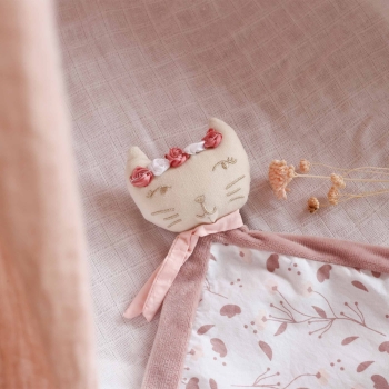 peluche rosa posata sul lettino del bebè con un piccolo fiore decorativo