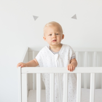 baby standing in bed with summer sleeping bag