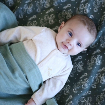 Baby with swaddles featuring tropical leaf patterns Baby with swaddles featuring tropical leaf patterns