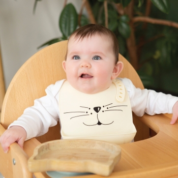 Baby in high chair with sand-colored little cat bib