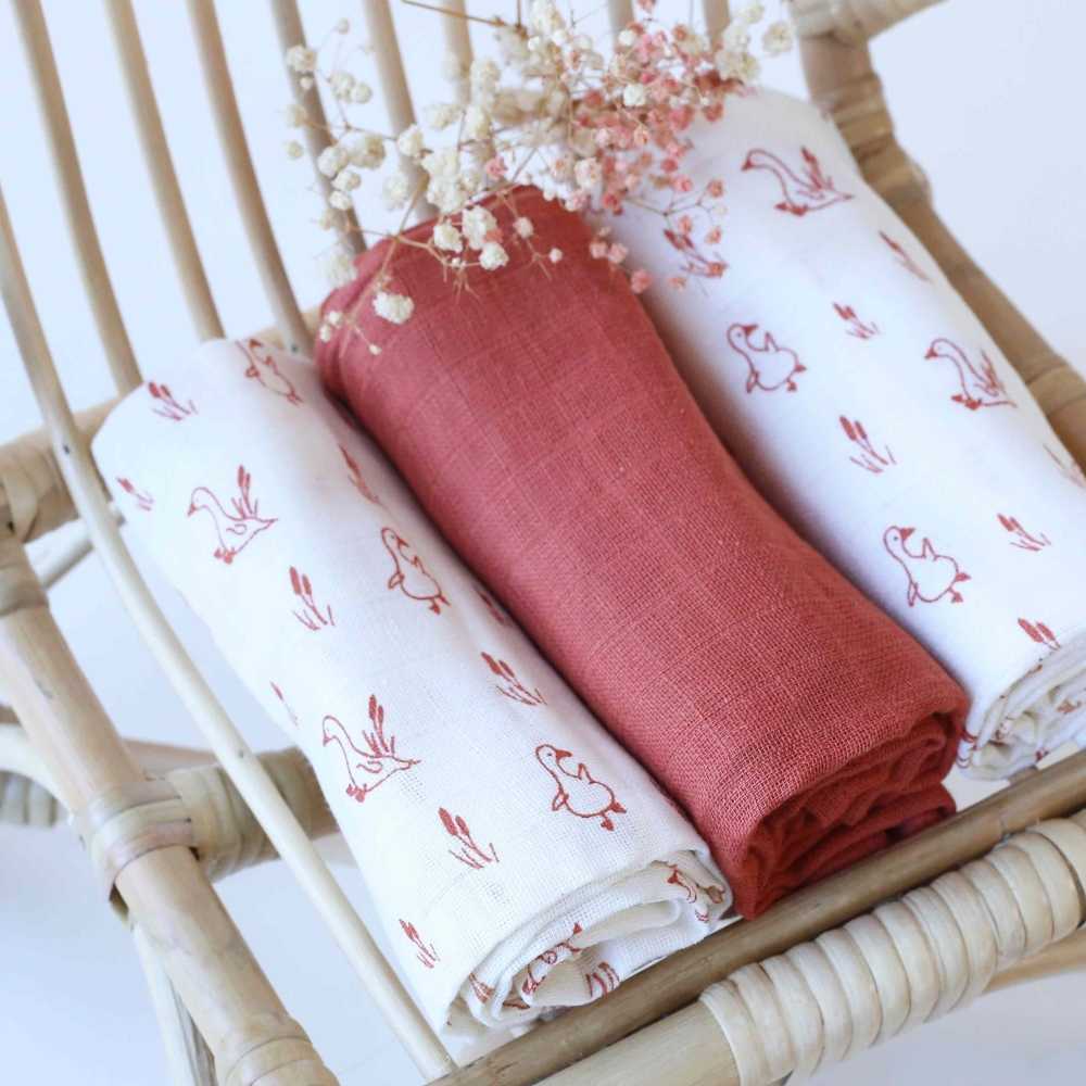 Conjunto de fraldas de pano sobre uma pequena cadeira de rotim para bebé Conjunto de fraldas de pano sobre uma pequena cadeira de rotim para bebé