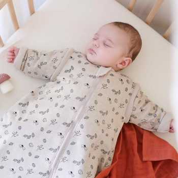 Bebé a dormir quentinho na cama, dentro do seu saco-cama com mangas e padrão de floresta Bebé a dormir quentinho na cama, dentro do seu saco-cama com mangas e padrão de floresta