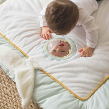 Baby looking at itself in the mirror of the activity mat Baby looking at itself in the mirror of the activity mat