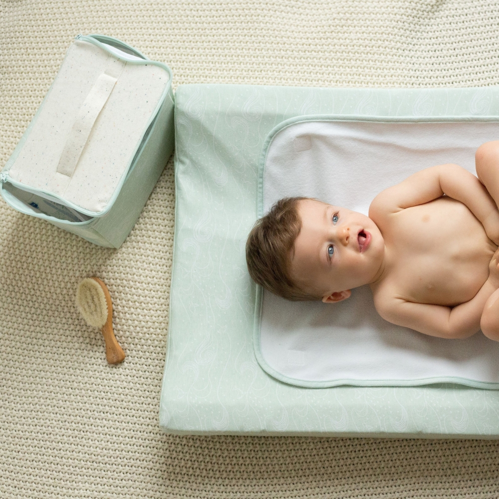 Baby on changing mat with vanity bag on the floor Baby on changing mat with vanity bag on the floor